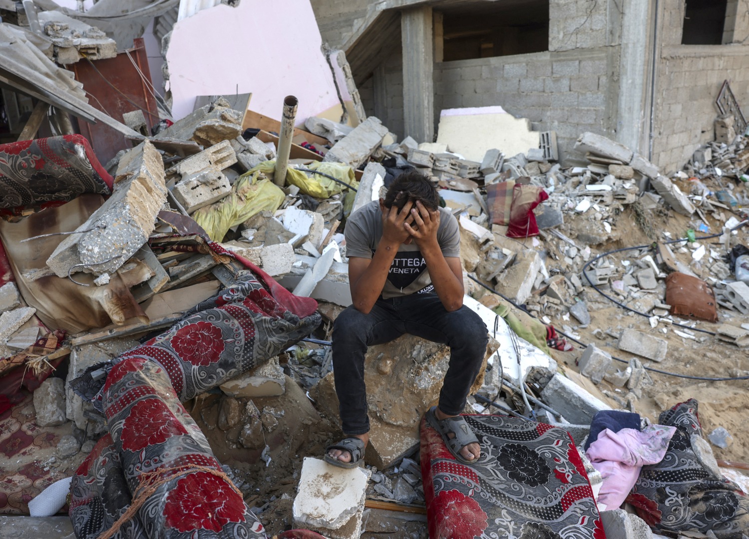 A Palestinian youth sits on the rubble of a destroyed home in the southern Gaza.