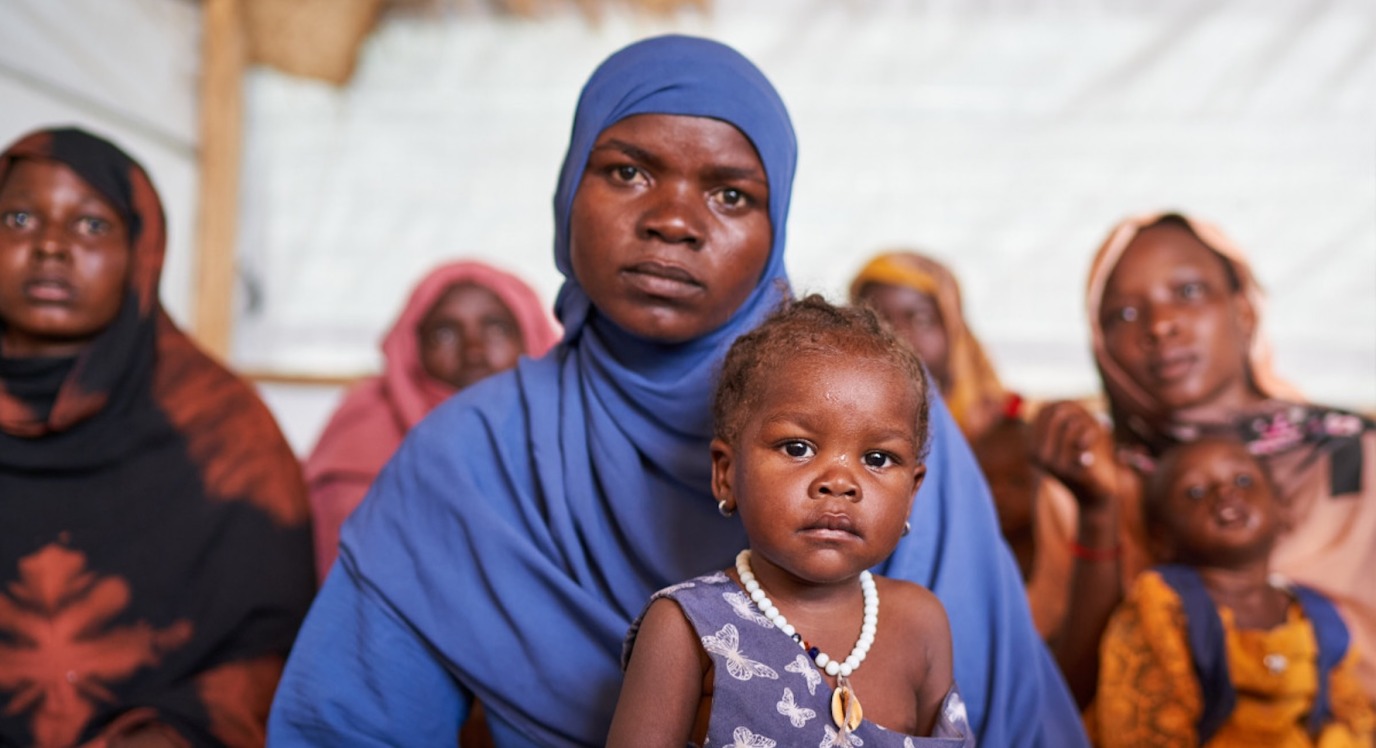 A mother with a headscarf holds her child.