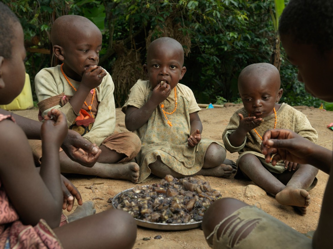 Children in Uganda enjoying a meal of cassava, beans, and leafy greens.