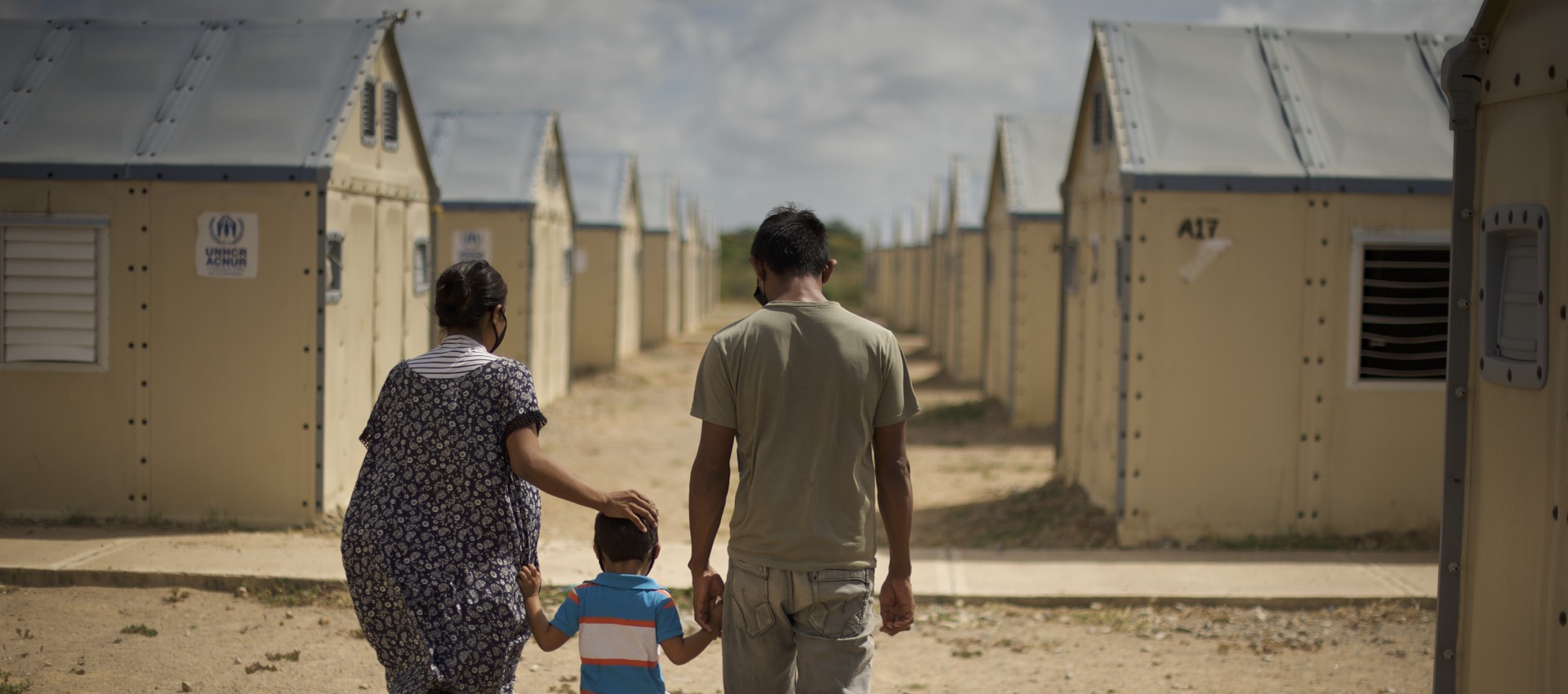 A family displaced by conflict walks through a settlement. Action Against Hunger is supporting families like these with cash transfers to help them buy food, medicine, and other goods.