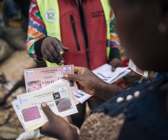 A woman holds her food vouchers up.