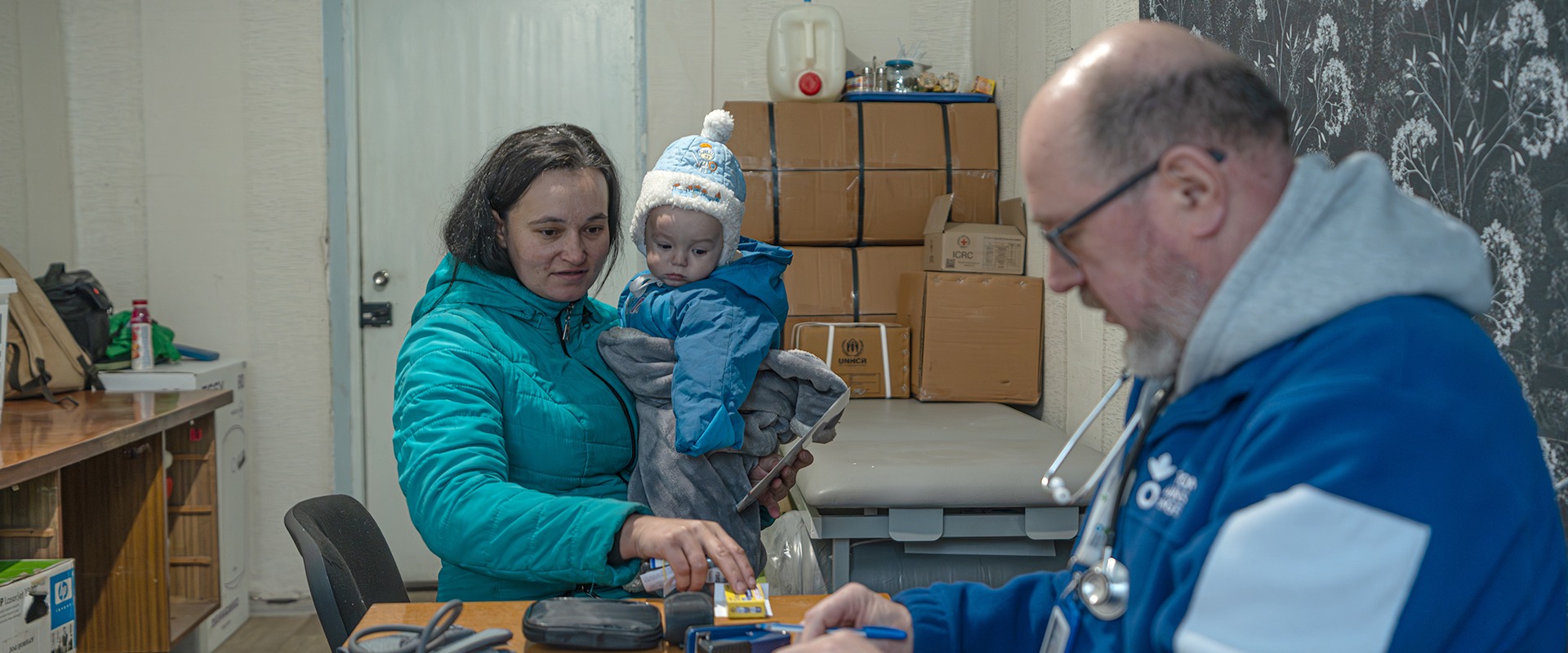 A woman holding her child next to an Action Against Hunger social worker in Ukraine.