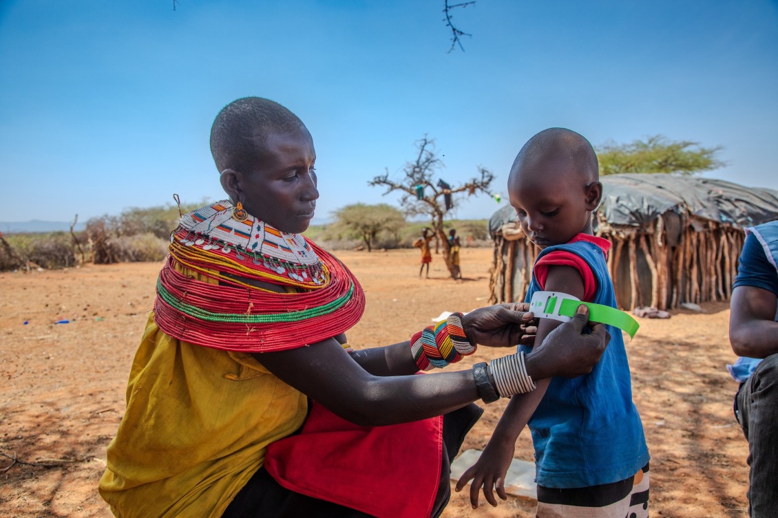 A woman screens a child for malnutrition in Kenya.