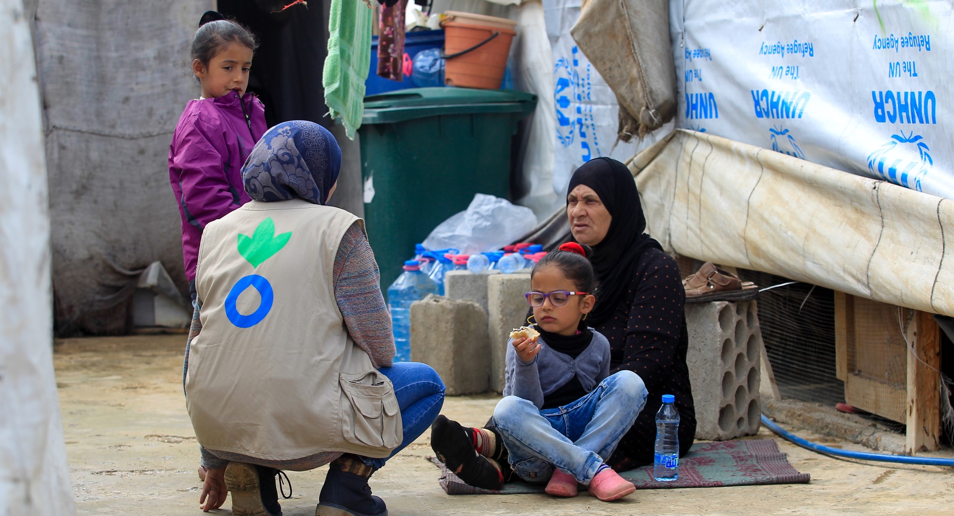 An Action Against Hunger aid worker talks with a refugee family in Lebanon.