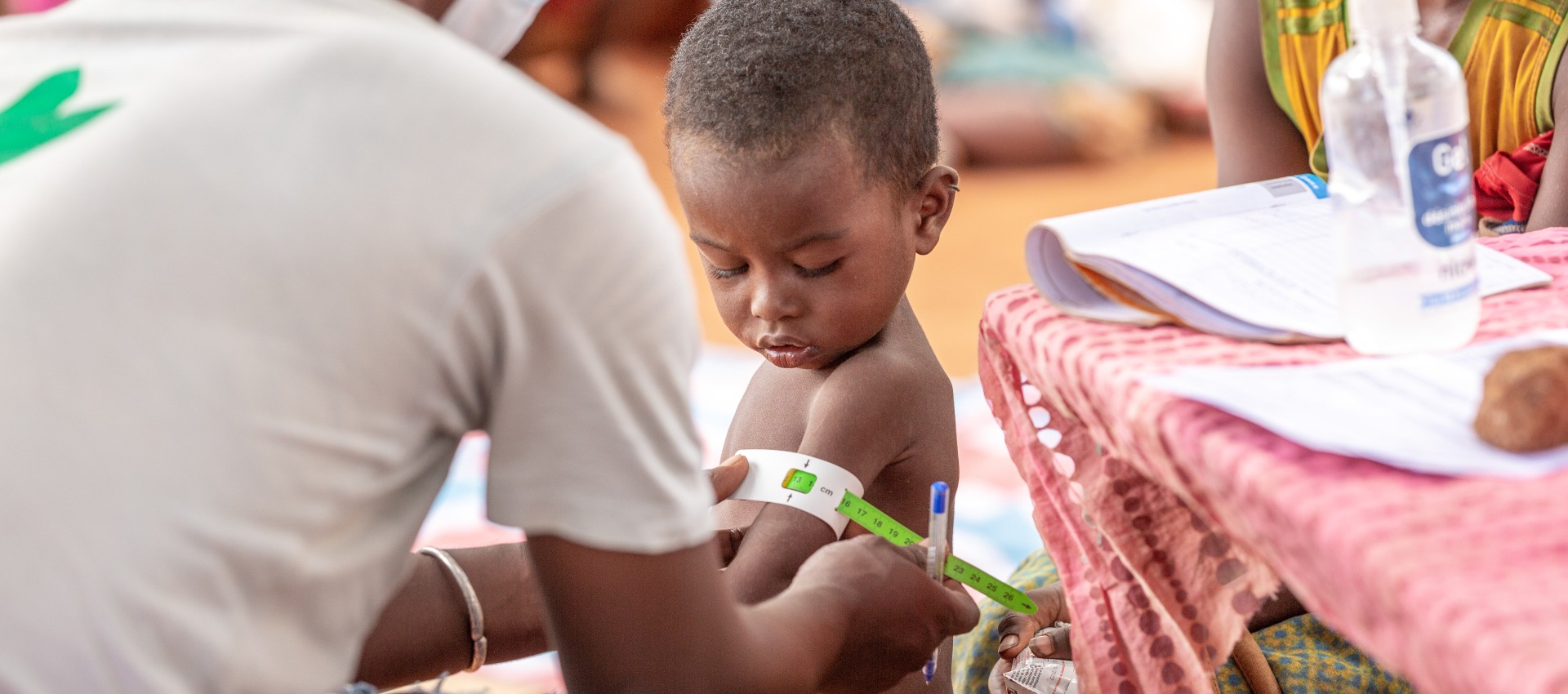 A boy is measured for malnutrition by an Action Against Hunger health worker.