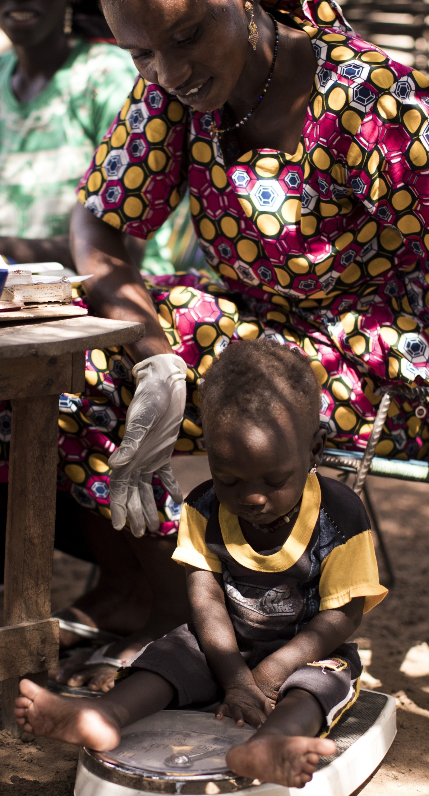 Hawa, an Action Against Hunger-trained community health worker, weighs a child as a part of a routine health check up.