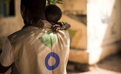 An Action Against Hunger Aid Worker holds a child in his arms in Mali.