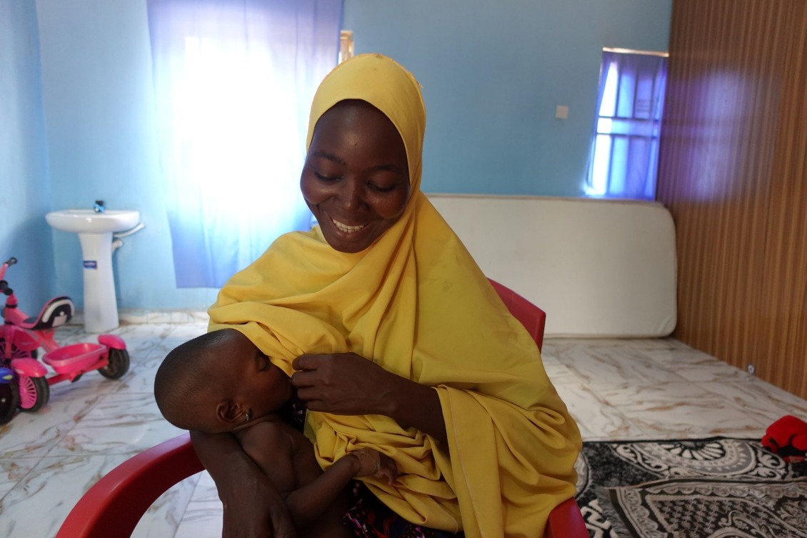 Yabiyatu Anas breastfeeds her 11-month-old baby who is recovering from SAM in a Nutrition Stabilization Center, supported and run by Action Against Hunger.