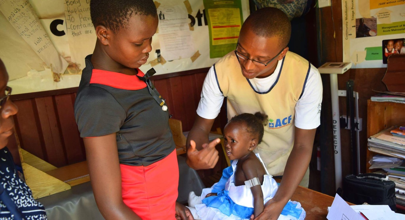 A community health worker in Isiolo County, Kenya shows a mother how to use a Click-MUAC device to screen her child for acute malnutrition.
