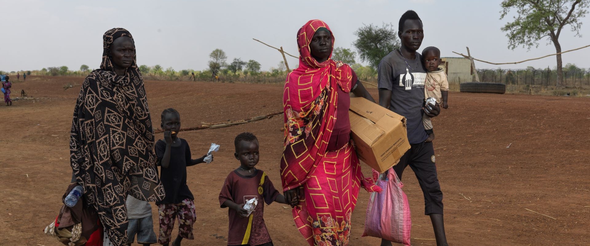 A group of six refugees walk with belongings near the South Sudan border