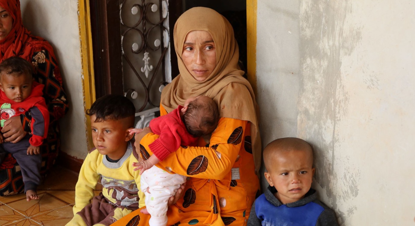 Syrian woman holds three small children.