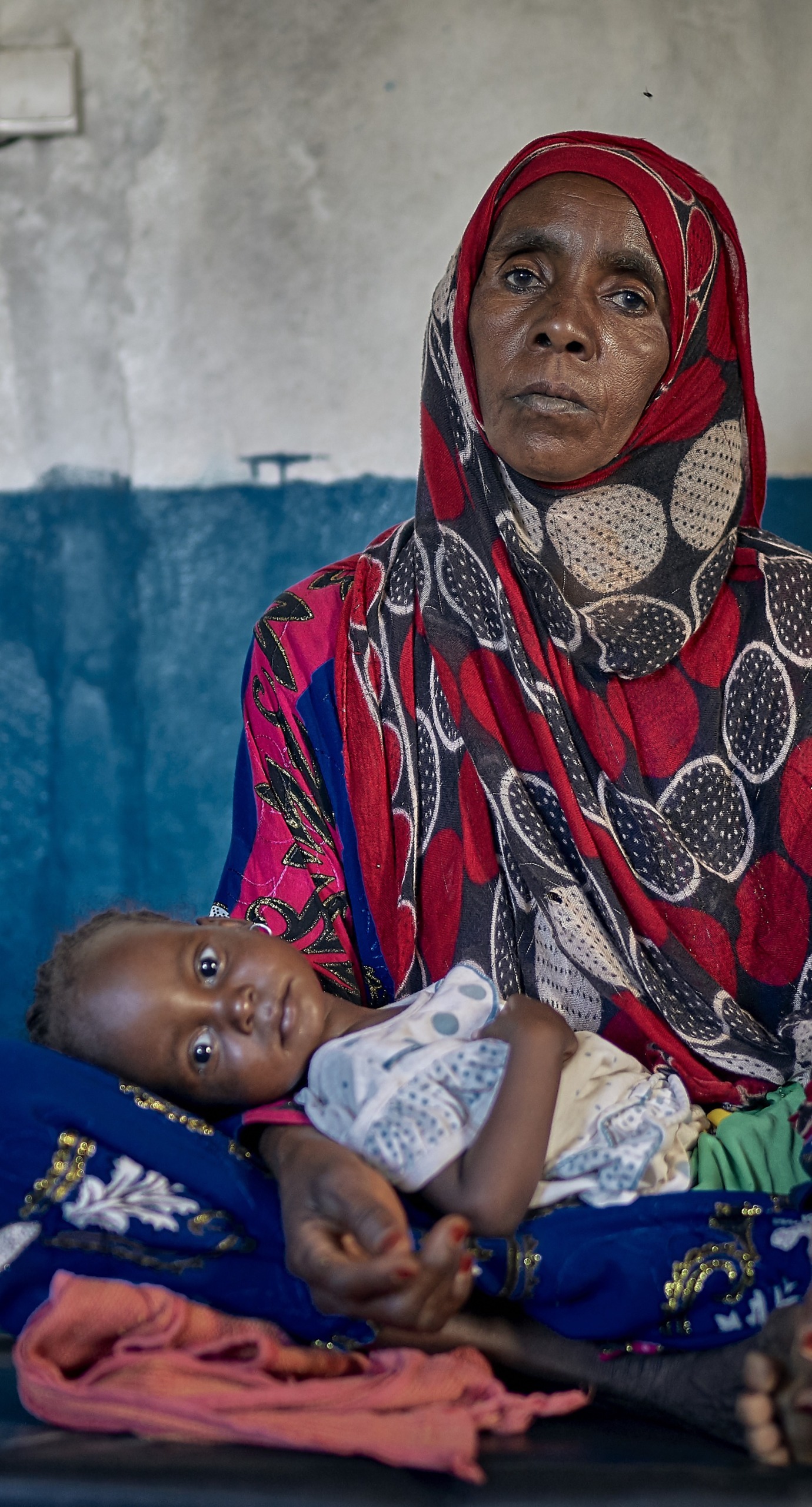 A woman holds her two year old granddaughter in her lap at an Action Against Hunger Health Center in Chad