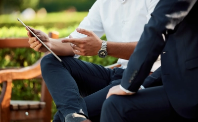 Stock image of a man sitting on a bench looking at a tablet.